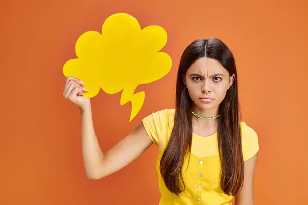 Frustriertes Teenager-Mädchen in lebendigem T-Shirt posiert mit gelber Gedankenblase und blickt in die Kamera — Stockfoto