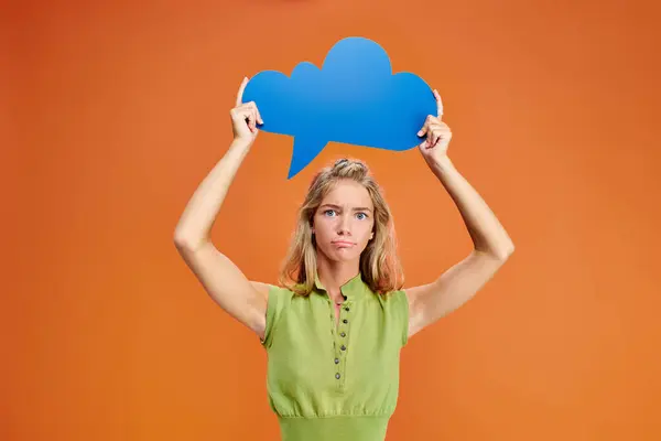 Confused adolescent girl in everyday outfit holding thought bubble above head and looking at camera — Stock Photo