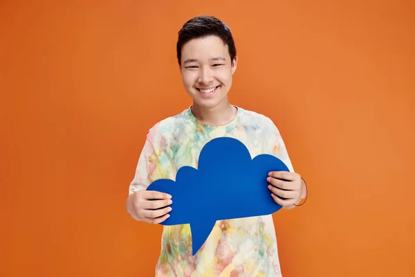 Alegre asiático adolescente menino no casual traje segurando azul pensamento bolha e olhando para a câmera — Fotografia de Stock