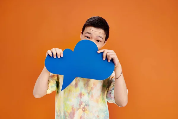 Jolly teenage asian boy in everyday vivid outfit looking at camera with thought bubble in hands — Stock Photo
