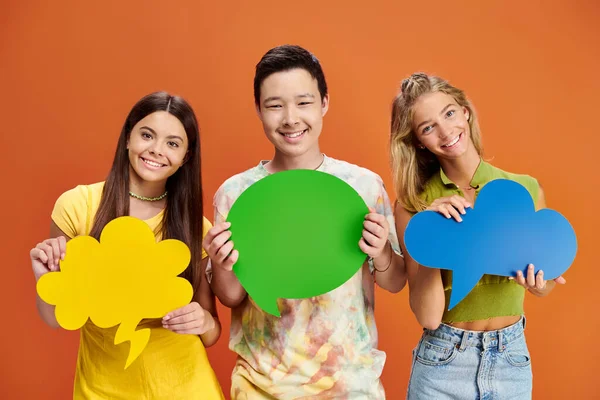 Cheerful adolescent interracial boy and girls holding thought and speech bubbles, friendship day — Stock Photo