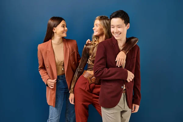 Joyeux brunette et blonde adolescentes souriant à l'autre à côté de leur élégant asiatique ami — Photo de stock