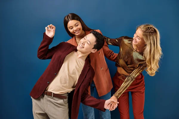 Fröhliche multirassische Teenager in stylischer Kleidung, die viel Spaß auf blauem Hintergrund haben, Freundschaftstag — Stockfoto