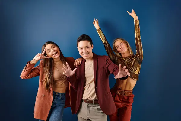 Adorable cheerful diverse teens in vibrant clothes having fun on blue backdrop, friendship day — Stock Photo