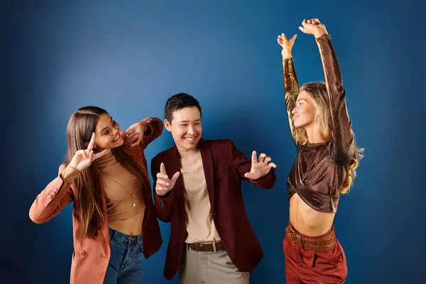 Joyous interracial teenage friends in fashionable clothes having fun on dark blue background — Stock Photo