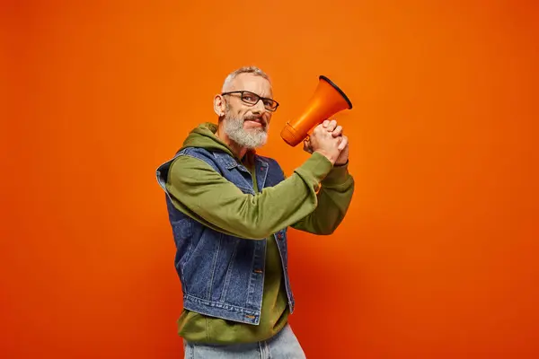 Funky gai modèle masculin mature avec barbe et lunettes posant avec mégaphone et regardant la caméra — Photo de stock