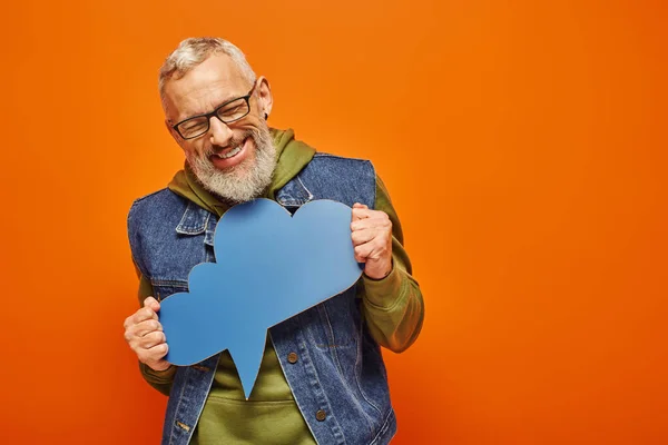 Cheerful good looking mature man in vibrant outfit with glasses holding thought bubble in his hands — Stock Photo