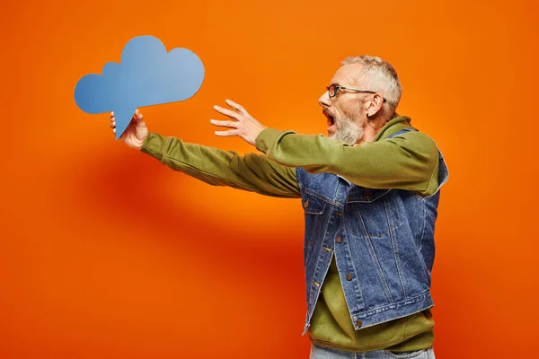 Shocked mature handsome man in vibrant hoodie and stylish holding thought bubble in his hand — Stock Photo