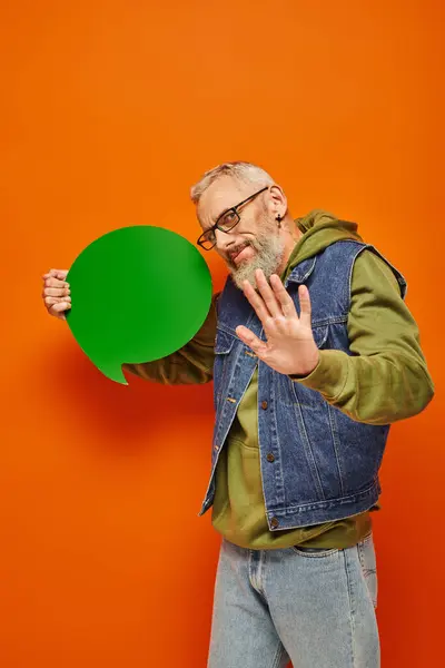 Good looking mature male model with glasses holding speech bubble and showing stop sign with palm — Stock Photo