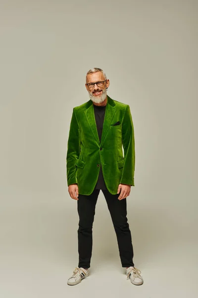 Joyeux beau mature homme avec barbe et lunettes en veston vert souriant joyeusement à la caméra — Photo de stock
