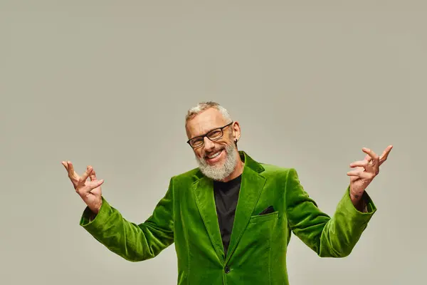 Весёлый красивый зрелый мужчина-модель в ярко-зелёном блейзере позирует и счастливо улыбается в камеру — стоковое фото