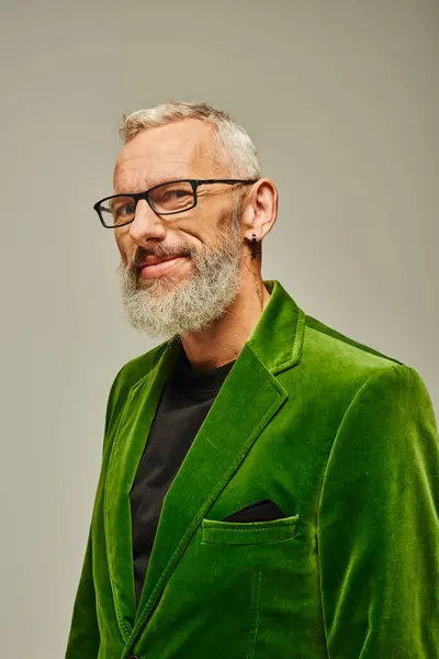 Guapo gris barbudo hombre maduro en verde elegante chaqueta con accesorios sonriendo a la cámara - foto de stock