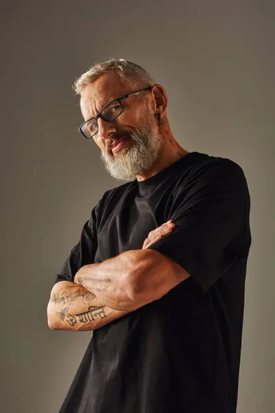Fröhliches älteres männliches Model in schwarzem T-Shirt posiert mit verschränkten Armen auf der Brust und lächelt in die Kamera — Stockfoto