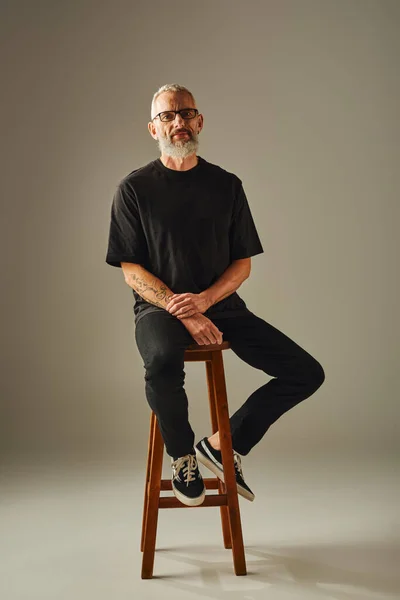 Schöne lustige ältere männliche Modell in schwarzem Hemd mit Brille und Tätowierungen Blick in die Kamera — Stockfoto