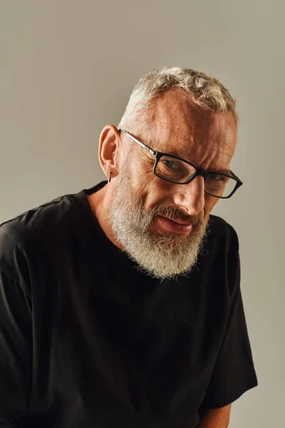 Porträt eines gut aussehenden, reifen Mannes mit Brille im schwarzen T-Shirt, der direkt in die Kamera blickt — Stockfoto