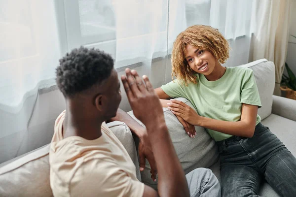 Sign language, cheerful african american woman in braces looking at boyfriend showing hand gesture — Stock Photo