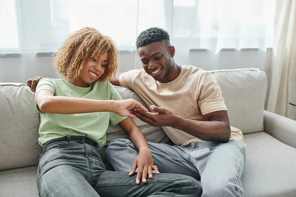 Концепція жестової мови, радісна афроамериканська пара торкається рук, сидячи на дивані — стокове фото