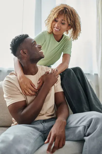 Happy african american woman embracing boyfriend in living room, black couple having quality time — Stock Photo