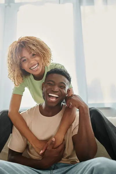 Freudige afrikanisch-amerikanische Frau umarmt Freund im Wohnzimmer, schwarzes Paar und Qualitätszeit — Stockfoto