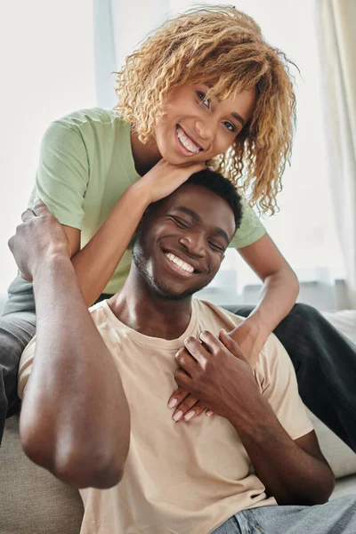 Junge afrikanisch-amerikanische Frau umarmt glücklichen Freund im Wohnzimmer, schwarzes Paar und Qualitätszeit — Stockfoto