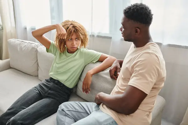 Афроамериканська жінка жестикулює, дивлячись на хлопця на дивані, невербальне спілкування — стокове фото