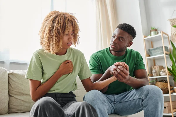 Young african american couple holding hands while sitting together on couch, emotional support — Stock Photo