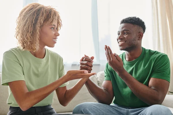 Glückliches afroamerikanisches Paar kommuniziert auf der Couch mit Gebärdensprache — Stockfoto
