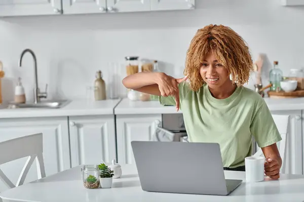 Cheerful african american woman using sign language during video call and holding cup of coffee — Stock Photo