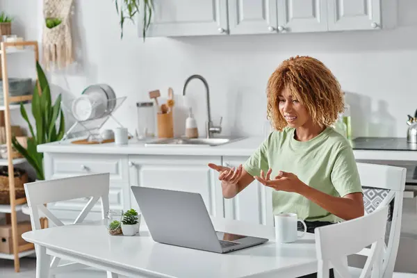 Alegre joven afroamericana mujer usando lenguaje de señas durante la videollamada en el ordenador portátil, conexión - foto de stock