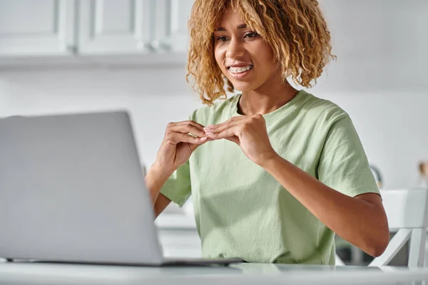 Smiling african american woman in braces using sign language during video call on laptop, connection — Stock Photo