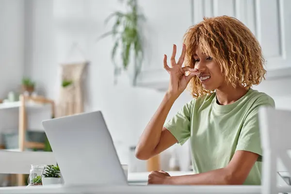 Joyeuse femme afro-américaine dans les bretelles en utilisant le langage des signes pendant le chat vidéo sur ordinateur portable, connexion — Photo de stock