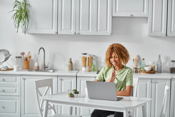 Felice donna afro-americana in apparecchio acustico utilizzando il linguaggio dei segni durante la videochiamata sul computer portatile, conversazione — Foto stock