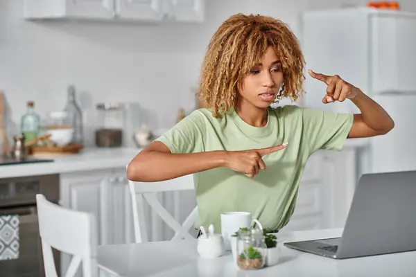 Focused african american woman in braces using sign language during video call on laptop, gesture — Stock Photo