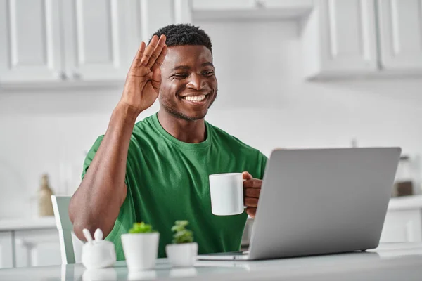 Африканский американец машет привет во время видеозвонка с ноутбуком, удаленной работой и фрилансером — стоковое фото
