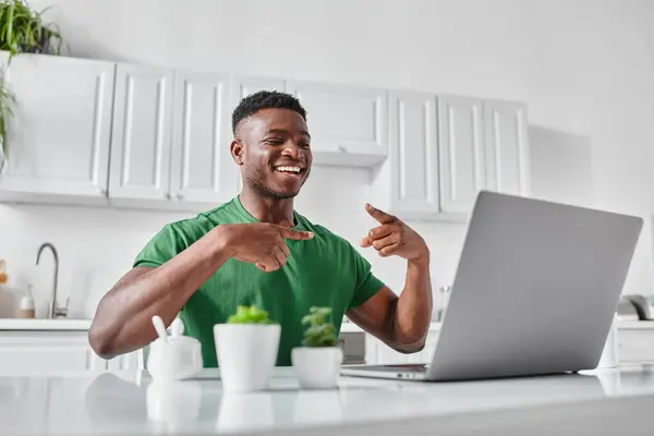 Alegre sordo afroamericano freelancer utilizando lenguaje de señas durante la videollamada en el ordenador portátil en casa - foto de stock
