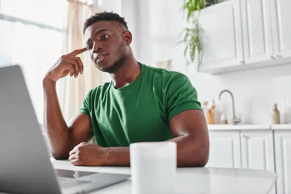 Bello e giovane uomo afroamericano utilizzando guardando webinar online di laptop a casa — Foto stock