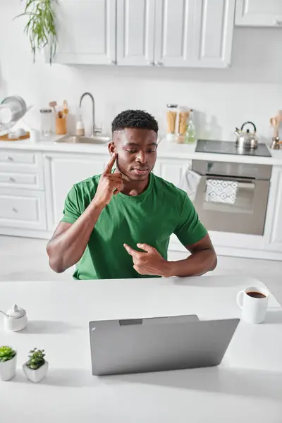 Глухий афроамериканський чоловік у зеленій футболці використовує мову жестів для спілкування під час відеодзвінка — стокове фото