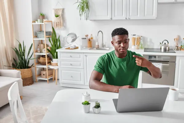 Homme afro-américain sourd en t-shirt vert utilisant le langage des signes pour la communication en ligne sur ordinateur portable — Photo de stock