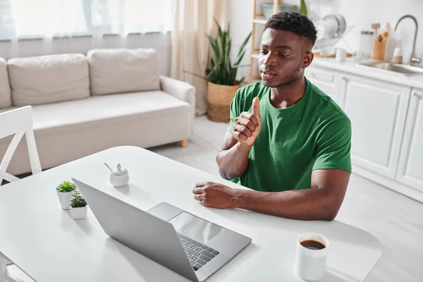 Hombre afroamericano sordo usando lenguaje de señas para la comunicación en línea en el ordenador portátil, chat de vídeo - foto de stock