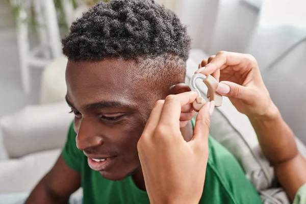 Afrikanisch-amerikanischer Mann lächelt, als seine Freundin ihm mit Hörgeräten, medizinischen Geräten hilft — Stockfoto