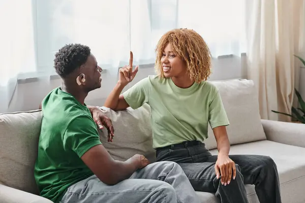 Африканська американська пара спілкується з жестовою мовою на дивані, чорний чоловік у слуховому апараті — Stock Photo