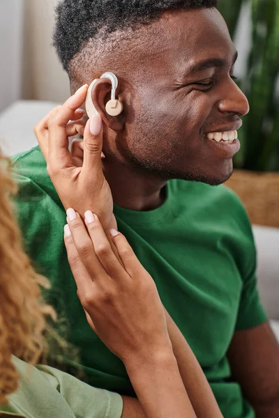Encaracolado Africano americano mulher vestindo aparelho auditivo dispositivo médico na orelha do namorado, acessibilidade — Fotografia de Stock