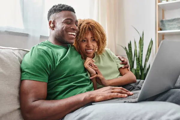 Happy african american couple walking movie on laptop, deaf man in hearing air and woman in braces — Stock Photo