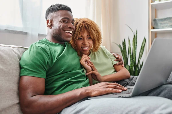 Glücklich afrikanisch-amerikanisches Paar zu Fuß Film auf Laptop, gehörloser Mann in Hörluft und Frau in Zahnspange — Stockfoto