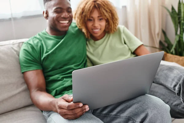 Smiling black couple walking movie on laptop, deaf man in hearing air and woman in braces — Stock Photo