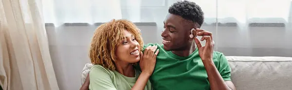 Felice uomo africano americano in apparecchio acustico seduto sul divano con fidanzata, banner — Foto stock