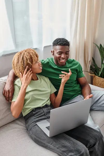 Happy african american woman in braces talking to deaf man with hearing aid device, laptop — Stock Photo
