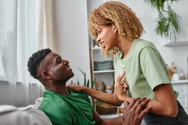 Portrait of cheerful deaf african american woman in hearing aid device smiling at boyfriend — Stock Photo