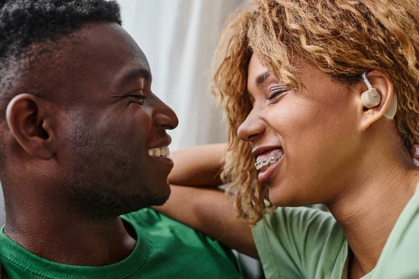 Close up of happy deaf african american woman in hearing aid device smiling near boyfriend at home — Stock Photo