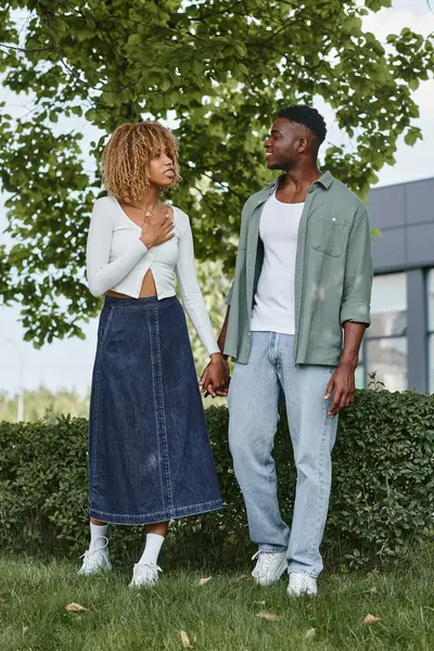 Happy african american couple holding hands and communicating with gestures outdoors — Stock Photo